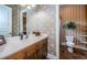 Charming bathroom with wood vanity, toilet, and patterned wallpaper at 9943 Milano Dr, Trinity, FL 34655