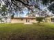 The back exterior shows a simple patio and double doors in a grassy backyard at 7206 Ashwood Dr, Port Richey, FL 34668