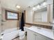Cozy bathroom with a tub, shower, tiled walls, unique mirror, and ample lighting at 7206 Ashwood Dr, Port Richey, FL 34668