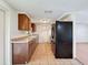 Kitchen features tile floors, wood cabinets, and a black refrigerator; open to the living area at 7206 Ashwood Dr, Port Richey, FL 34668