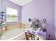 Bathroom showcasing a tub, window, vanity and make up storage on a purple wall and desk at 11143 Merganser Way, New Port Richey, FL 34654
