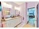 Bathroom with double sinks, pink walls, a glass shower, and an open door to the bedroom at 11143 Merganser Way, New Port Richey, FL 34654