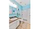 Bright blue bathroom with a shower-tub combo, vanity and updated mirror, with neutral tile floor at 11143 Merganser Way, New Port Richey, FL 34654