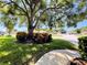Landscaped front yard featuring mature trees, lush grass, and colorful ornamental plants at 13626 Bryndlewood Ct, Hudson, FL 34669