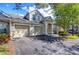 Tan two-story townhome with a two-car garage and mature trees in the front yard at 3605 Kings Rd # 102, Palm Harbor, FL 34685