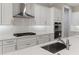 Well-lit kitchen featuring stainless steel hood, cooktop, and sink with white cabinets and subway tile backsplash at 3898 Southern Valley Loop, Brooksville, FL 34601