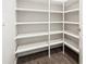 Walk-in pantry with white painted shelving and dark wood flooring next to a white door at 3898 Southern Valley Loop, Brooksville, FL 34601