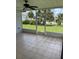 Screened-in patio features neutral tile, a ceiling fan, and a view of the home's landscaping and neighboring properties at 7332 Mako Dr, Hudson, FL 34667