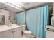 Bathroom with light blue shower curtain and white vanity at 12119 Sunny Glen Ln # H1, Hudson, FL 34669