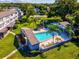 Aerial view of community pool, patio area with lounge chairs, and lush landscaping at 1127 King Arthur Ct # 305, Dunedin, FL 34698