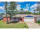 Charming single-story home with red brick, blue and white accents, complemented by a lush green lawn and mature trees at 3849 Claremont Dr, New Port Richey, FL 34652