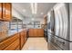 Bright kitchen with stainless steel refrigerator, wooden cabinets, tile backsplash, and a view of the patio at 3849 Claremont Dr, New Port Richey, FL 34652