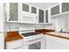 White kitchen with unique glass-tiled cabinets and gas stove at 10221 Elgin Blvd, Spring Hill, FL 34608