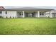 View of the backyard with a spacious covered patio, sliding glass doors and well-manicured lawn at 19395 Sheltered Hill Dr, Brooksville, FL 34601