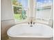 Bright bathroom featuring a luxurious soaking tub and a view to the outside through multiple windows at 19395 Sheltered Hill Dr, Brooksville, FL 34601