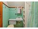 Small bathroom with teal tile, shower, and vintage vanity at 14335 Snow Memorial Hwy, Brooksville, FL 34601