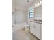 Clean bathroom with a tub-shower combo, white cabinetry, and neutral-toned tiled floors at 11512 Weaver Hollow Rd, New Port Richey, FL 34654