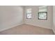 A bright bedroom with neutral carpeting and baseboards, and two windows with black trim at 11512 Weaver Hollow Rd, New Port Richey, FL 34654