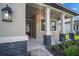 Inviting front porch with stone-accented columns, modern lighting, and an elegant glass front door at 11512 Weaver Hollow Rd, New Port Richey, FL 34654