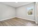 Bright bedroom with light gray walls, a light wood floor, a window, and white trim at 6109 Dusk Rose Ln, Brooksville, FL 34601