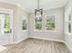 Dining room with a modern chandelier, gray-tone floors, and three windows at 6109 Dusk Rose Ln, Brooksville, FL 34601