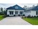 Charming single-story home boasting manicured landscaping, a paver driveway, and a modern blue and white exterior at 6109 Dusk Rose Ln, Brooksville, FL 34601