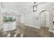 Spacious living area featuring wood floors, tray ceiling, modern light fixture, and sliding glass doors at 6109 Dusk Rose Ln, Brooksville, FL 34601