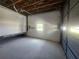 Bright garage interior, featuring concrete floor, overhead wood beams, and a large rolling door at 6428 Driftwood Dr, Hudson, FL 34667
