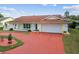 Charming single-story home featuring a red driveway and attached two-car garage in a well-maintained yard at 12212 Buttonwood Row, Hudson, FL 34667