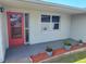 Front porch featuring a red door, decorative plants, and a nearby window at 3544 Wilson Dr, Holiday, FL 34691