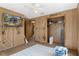 Bedroom with wood paneling, ceiling fan, and large TV at 8812 Camp Ln, Hudson, FL 34667