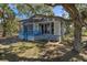 Blue cottage exterior with mature trees and landscaping at 8812 Camp Ln, Hudson, FL 34667