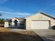 Beige house with a white garage door and a small front yard at 15645 Olney Ln, Spring Hill, FL 34610