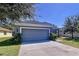 Gray exterior, lush landscaping, and a two-car garage characterize this charming one-story house at 14512 Balloch Dr, Hudson, FL 34667