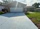 Charming single-story home with a well-manicured lawn and a long, painted driveway leading to an attached garage at 10521 Mira Vista Dr, Port Richey, FL 34668