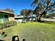 View of home's yard, featuring a grassy area with some trees in the background at 10521 Mira Vista Dr, Port Richey, FL 34668