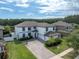 Stunning aerial view of a two-story home with a long driveway, lush lawn, and beautiful landscaping, backing onto a serene lake at 12135 Crestridge Loop, Trinity, FL 34655