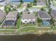 Aerial view of the home with a white fence bordering the property, adjacent to a serene lake and a screened pool at 12135 Crestridge Loop, Trinity, FL 34655