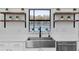 Bright kitchen featuring stainless steel farmhouse sink, modern fixtures, open shelving, and a view of the water at 12135 Crestridge Loop, Trinity, FL 34655