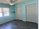 Sunlit bedroom with two closets, wood-look flooring and a ceiling fan at 3018 Greynolds Ave, Spring Hill, FL 34608