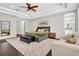 Spacious main bedroom featuring a tray ceiling, ceiling fan, and a cozy seating area at 6120 Marsh Trail Dr, Odessa, FL 33556