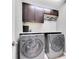 Convenient laundry room with modern washer and dryer, ample cabinets, and overhead lighting at 12135 Crestridge Loop, Trinity, FL 34655