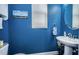 Stylish powder room featuring blue walls, a round mirror, and modern fixtures at 10595 Marsha Dr, New Port Richey, FL 34655