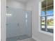 Modern bathroom featuring a glass shower with white subway tile, and a bright window with a view at 19364 Sheltered Hill Dr, Brooksville, FL 34601