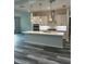 Modern kitchen with a large island, stainless appliances, pendant lighting, and gray plank flooring at 19364 Sheltered Hill Dr, Brooksville, FL 34601