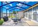 Relaxing screened patio featuring a table and chairs, grill, and comfortable lounge chairs at 8704 Cypress Lakes Blvd, New Port Richey, FL 34653