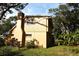 Tan house exterior with a chimney and large trees in the yard at 15473 Darien Way, Clearwater, FL 33764