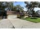 Tan house with brown roof, attached garage, and brick driveway at 15473 Darien Way, Clearwater, FL 33764