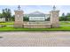 Community entrance with decorative brick columns, lush landscaping, and an ornate iron gate at 6392 Summit View Dr, Brooksville, FL 34601