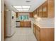 View of kitchen with wood cabinets, white appliances, and tiled floor at 7719 Cosme Dr # 1, Hudson, FL 34667